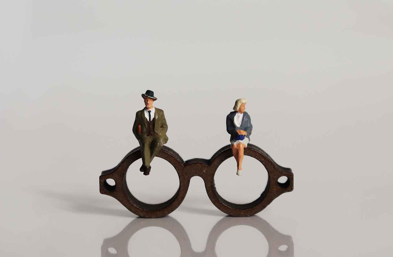 a small male and female figure are sitting on a pair of glasses